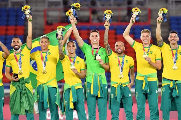 Brazil's gold medallists Matheus Cunha, Richarlison, Antony, goalkeeper Brenno, Dani Alves, Bruno Fuchs and Marcilio Nino celebrate on the podium during the medal ceremony of the Tokyo 2020 Olympic Games men's football competition at Yokohama International Stadium in Yokohama, Japan, on August 7, 2021. (Photo by Tiziana FABI / AFP)