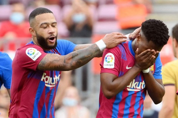 Barcelona's Spanish midfielder Ansu Fati celebrates with Barcelona's Dutch forward Memphis Depay (L) after scoreing his team's third goal during the Spanish League football match between FC Barcelona and Levante UD at the Camp Nou stadium in Barcelona on September 26, 2021. (Photo by LLUIS GENE / AFP)