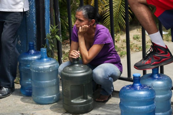 A woman waits to fill cans with potable water in Caracas on March 10, 2019, during the third day of a massive power outage which has left Venezuelans without communications, electricity and water. - The unprecedented power outage already left 15 patients dead and threatens to extend indefinitely, increasing distress for the severe political and economic crisis hitting the oil-rich South American nation. (Photo by Cristian HERNANDEZ / AFP)