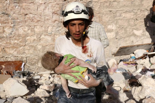 A Syrian civil defence worker carries a child who was retrieved under the rubble of a collapsed building following a reported air strike on the rebel-held neighbourhood of Sakhur in the northern city of Aleppo on July 19, 2016.Civilians in rebel-held parts of Syria's Aleppo expressed fears on July 18, 2016 of a lengthy government siege, as food supplies dwindled after regime troops seized the only road into the city's east. The government advance, which has been backed by a Russian air offensive, is seen as a major setback for opposition forces in Syria's second city. / AFP PHOTO / THAER MOHAMMED