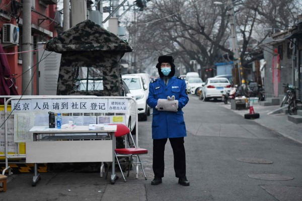 A security guard wears a facemask to protect against the COVID-19 coronavirus as he stands guard at a checkpoint at the entrance to an alley in Beijing on February 20, 2020. - China on February 20 touted a big drop in new virus infections as proof its epidemic control efforts are working, but the toll grew abroad with deaths in Japan and South Korea. (Photo by Greg Baker / AFP)