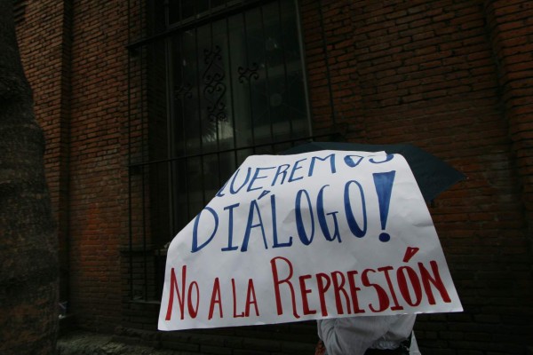 A person holds a sign reading 'We want dialogue! No to repression' during a teachers march in Oaxaca, Mexico on June 20, 2016. Thousands of teachers protested in southern Mexico on Monday to denounce the deaths of eight people after violent weekend clashes that police blamed on unidentified gunmen. / AFP PHOTO / Hector GUERRERO