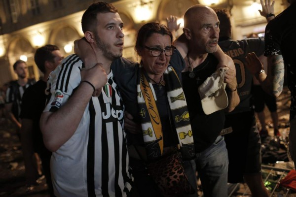 TOPSHOT - Juventus' supporters evacuate the Piazza San Carlo after a panic movement in the fanzone where thousands of Juventus fans watched the UEFA Champions League Final football match between Juventus and Real Madrid on a giant screen, on June 3, 2017in Turin. / AFP PHOTO / Marco BERTORELLO