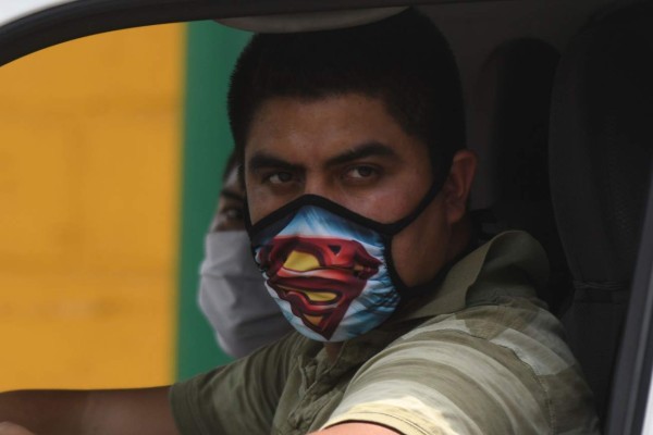 A driver wearing a face mask as a preventive measure against the spread of new COVID-19 coronavirus, stares at a crime scene after a man was shot dead by unidentified gunmen, in Guatemala City, on April 14, 2020. - Guatemala's President Alejandro Giammattei extended -until April 19- the partial curfew in force to contain the advance of the new coronavirus, which up to now has 156 people infected and five dead. (Photo by Johan ORDONEZ / AFP)