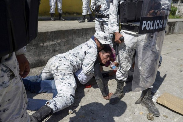 TOPSHOT - A Central American migrant - part of a group of mostly Hondurans travelling on caravan to the US- is detained by a member of Mexico's National Guard after crossing the Suichate River, the natural border between, Guatemala, with Ciudad Hidalgo, Mexico, on January 20, 2020. - Hundreds of Central Americans from a new migrant caravan tried to enter Mexico by force Monday by crossing the river that divides the country from Guatemala, prompting the National Guard to fire tear gas, an AFP correspondent said. (Photo by ISAAC GUZMAN / AFP)