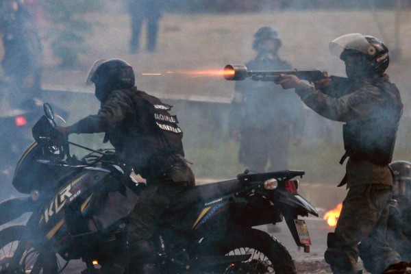 Bolivarian National Guard members shoot rubber bullets at Venezuelan opposition demonstrators blocking the avenue, during a protest against President Nicolas Maduro, in Caracas, on July 6, 2017. A political and economic crisis in the oil-producing country has spawned often violent demonstrations by protesters demanding Maduro's resignation and new elections. The unrest has left 91 people dead since April 1. / AFP PHOTO / FEDERICO PARRA
