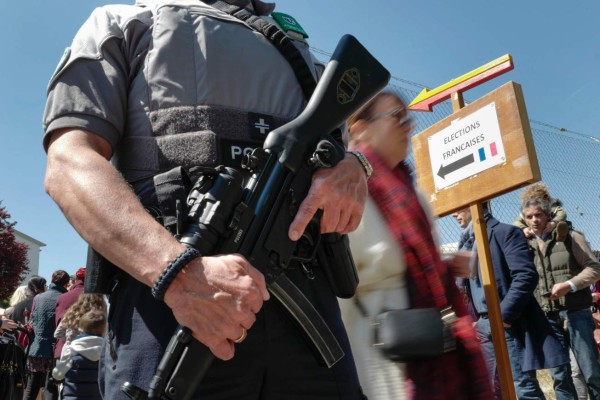 A Swiss police officer guards the entrance of a polling station for French citizen living in Switzerland during the first round of the French Presidential election on April 23, 2017 in Geneva. / AFP PHOTO / Fabrice COFFRINI