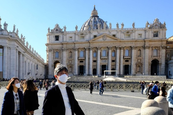 Tourists wearing a protective masks walk in St. Peter's square at the Vatican on February 28, 2020. - Italy urged tourists spooked by the novel coronavirus COVID-19 not to stay away, but efforts to reassure the world it was managing the outbreak were overshadowed by confusion over case numbers. (Photo by ANDREAS SOLARO / AFP)