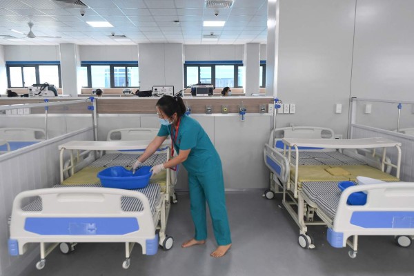 A medical worker sets up beds in the under-construction 500-bed field hospital for Covid-19 coronavirus patients in Hanoi on August 30, 2021. (Photo by Nhac NGUYEN / AFP)