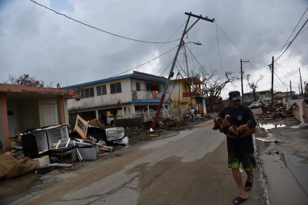 A man walks in a street next to damaged houses in Punta Santiago, in Humacao, in the east of Puerto Rico, on September 27, 2017, one week after the passage of Hurricane Maria.The US island territory, working without electricity, is struggling to dig out and clean up from its disastrous brush with the hurricane, blamed for at least 33 deaths across the Caribbean. / AFP PHOTO / HECTOR RETAMAL