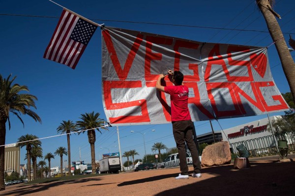 LAS VEGAS, NV - OCTOBER 5: A man writes a note on a 'Vegas Strong' banner that hangs near the 'Welcome to Fabulous Las Vegas' sign at the south end of the Las Vegas Strip, October 5, 2017 in Las Vegas, Nevada. On October 1, Stephen Paddock killed at least 58 people and injured more than 450 after he opened fire on a large crowd at the Route 91 Harvest country music festival. The massacre is one of the deadliest mass shooting events in U.S. history. Drew Angerer/Getty Images/AFP== FOR NEWSPAPERS, INTERNET, TELCOS & TELEVISION USE ONLY ==