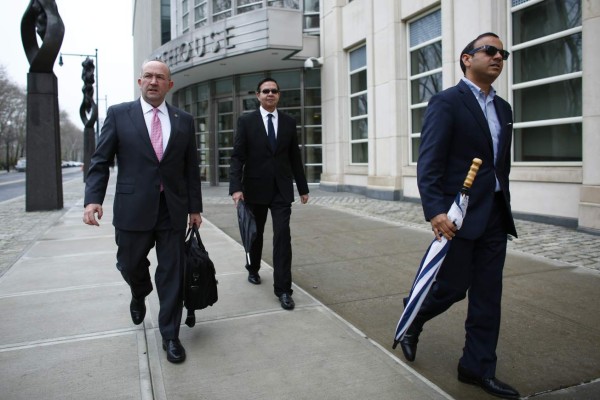 Former Honduran president Rafael Callejas (C) leaves the Brooklyn federal court in New York, March 28, 2016 after pleading guilty to charges of racketeering conspiracy and wire fraud conspiracy in connection with the FIFA corruption scandal. / AFP / KENA BETANCUR
