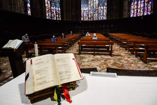 People attend a mass at the Cappella Feriale of the Duomo cathedral in Milan on May 18, 2020 during the country's lockdown aimed at curbing the spread of the COVID-19 infection, caused by the novel coronavirus. - Restaurants and churches reopen in Italy on May 18, 2020 as part of a fresh wave of lockdown easing in Europe and the country's latest step in a cautious, gradual return to normality, allowing businesses and churches to reopen after a two-month lockdown. (Photo by Miguel MEDINA / AFP)