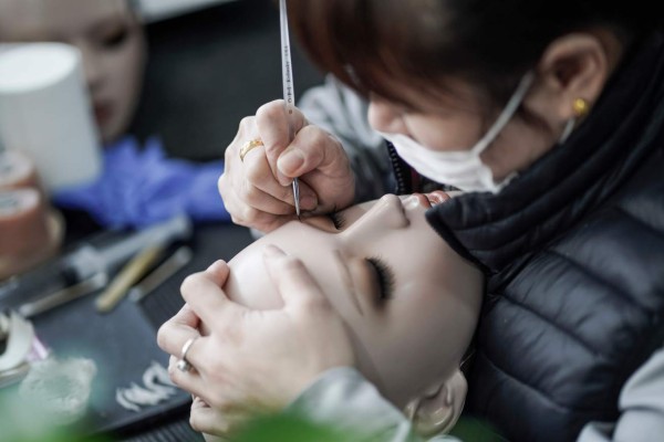 This photo taken on February 1, 2018 shows a worker painting the face of a silicone doll at a factory of EXDOLL, a firm based in the northeastern Chinese port city of Dalian.With China facing a massive gender gap and a greying population, a company wants to hook up lonely men and retirees with a new kind of companion: 'Smart' sex dolls that can talk, play music and turn on dishwashers. / AFP PHOTO / FRED DUFOUR / TO GO WITH China-sex-lifestyle, FOCUS by Joanna CHIU
