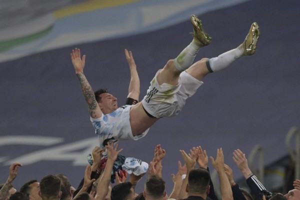 Argentina's Lionel Messi is thrown into the air by teammates after winning the Conmebol 2021 Copa America football tournament final match against Brazil at Maracana Stadium in Rio de Janeiro, Brazil, on July 10, 2021. (Photo by CARL DE SOUZA / AFP)