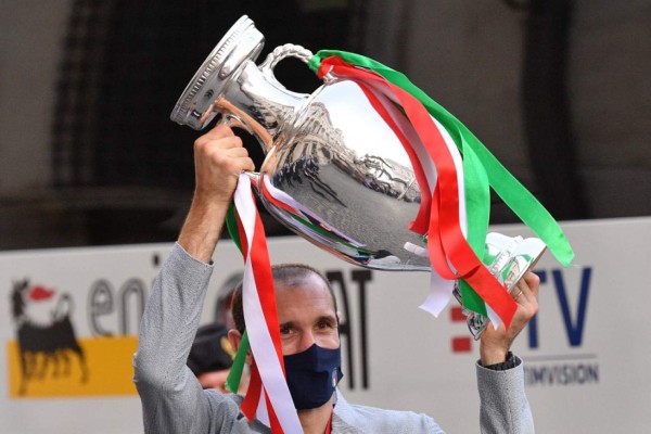 Italy's defender Giorgio Chiellini holds the UEFA EURO 2020 trophy as he gets down the bus transporting players and staff of Italy's national football team arriving to attend a ceremony at the prime minister's office Palazzo Chigi in Rome on July 12, 2021, a day after Italy won the UEFA EURO 2020 final football match between Italy and England. (Photo by Tiziana FABI / AFP)