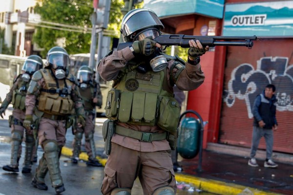 A riot policeman shoots at demonstrators during protests in Valparaiso, Chile, on October 20, 2019. - Fresh clashes broke out in Chile's capital Santiago on Sunday after two people died when a supermarket was torched overnight as violent protests sparked by anger over economic conditions and social inequality raged into a third day. (Photo by JAVIER TORRES / AFP)