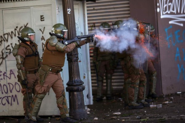 Riot police clash with demonstrators during protests in Santiago, on October 20, 2019. - Fresh clashes broke out in Chile's capital Santiago on Sunday after two people died when a supermarket was torched overnight as violent protests sparked by anger over economic conditions and social inequality raged into a third day. (Photo by Pablo VERA / AFP)