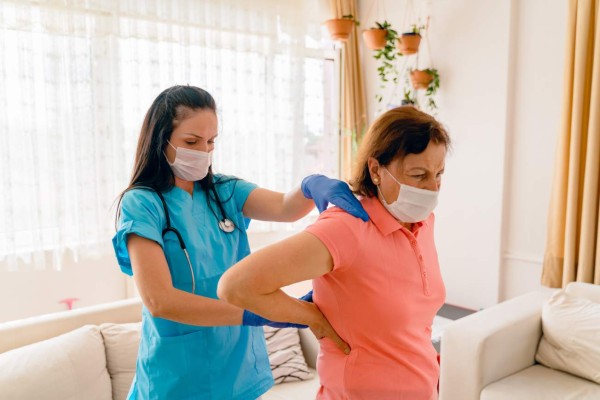 Senior adult, female patient does arm exercises with her home healthcare nurse or physical therapist in nursing home or home setting