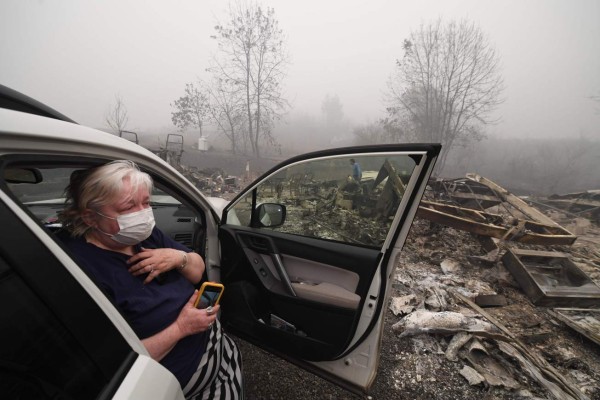 TOPSHOT - Margi Wyatt reacts after returning to find her mobile home destroyed by wildfire as her husband Marcelino Maceda (background) searches in the ruins in Estacada, Oregon September 12, 2020. - US officials girded today for the possibility of mass fatalities from raging wildfires up and down the West Coast, as evacuees recounted the pain of leaving everything behind in the face of fast-moving flames. Dense smog from US wildfires that have burnt nearly five million acres and killed 27 people smothered the West Coast on September 12. (Photo by Robyn Beck / AFP)