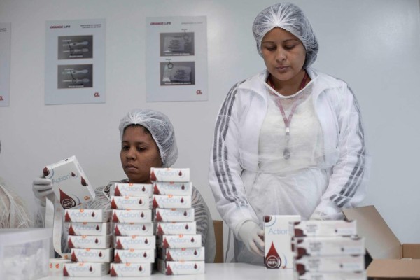 Women pack HIV self-test kits at OrangeLife factory in Rio de Janeiro, Brazil on July 07, 2017. Brazil started selling, for the first time, HIV detection tests in pharmacies nationwide. / AFP PHOTO / Mauro PIMENTEL / TO GO WITH AFP STORY