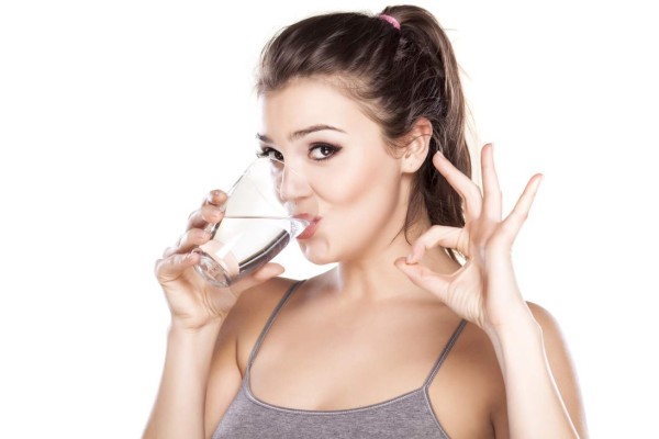 young beautiful woman drinks water from a glass and shows with her fingers sign for delicious