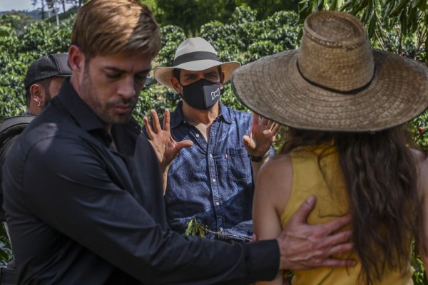 TV director Mauricio Cruz (C) rehearses a scene with Colombian actress Laura Londono (R) and Cuban actor William Levy (L) during the production of a new version of the Colombian soap opera Cafe in the municipality of Chinchina, Caldas Department, Colombia, on December 8, 2020, amid the COVID-19 coronavirus pandemic. - Soap operas revive in Colombia, one of the major references of this industry in Latin America, after the paralysis by the pandemic. They are produced with asepsis, covid-19 tests, restriction in the capacity, masks, anti-fluid suits, adjusted budgets by the crisis and a permanent risk. According to the National Media Association (Asomedios), the confinement decreed by the government at the end of March forced RCN and its competitor Caracol to stop 38 productions. (Photo by Joaquin SARMIENTO / AFP)
