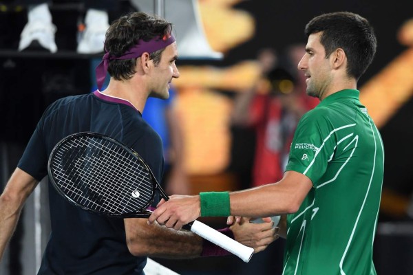 El serbio Novak Djokovic (R) se da la mano con el suizo Roger Federer al final del partido de semifinales de singles masculinos el día once del torneo de tenis Open de Australia en Melbourne el 30 de enero de 2020.