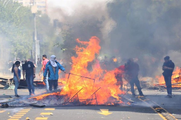 SANTIAGO (CHILE), 19/10/2019.- Manifestantes queman objetos durante una protesta contra el incremento del precio en los billetes del metro, este sábado en Santiago (Chile). Durante la semana, las protestas por el incremento del precio del billete del metro de Santiago de Chile fueron en aumento hasta derivar en disturbios e incidentes violentos. EFE/ Elvis González