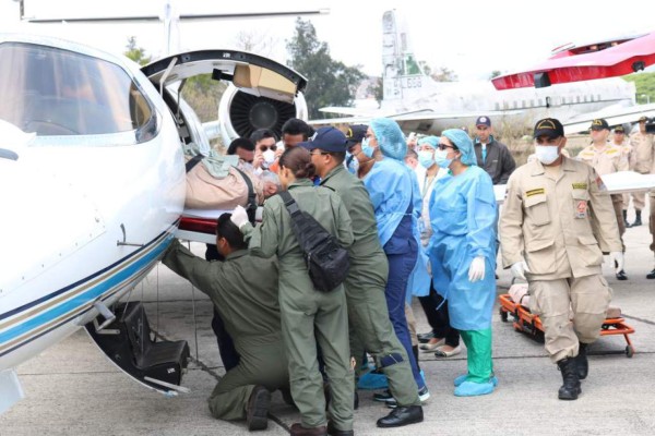 Momento en el que trasladaban a tres bomberos hondureños, dos de los cuales ya murieron. Foto de archivo.