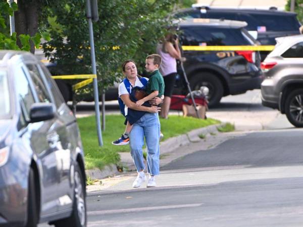 Una madre recoge a su hijo tras el tiroteo en una escuela católica de Minneapolis.