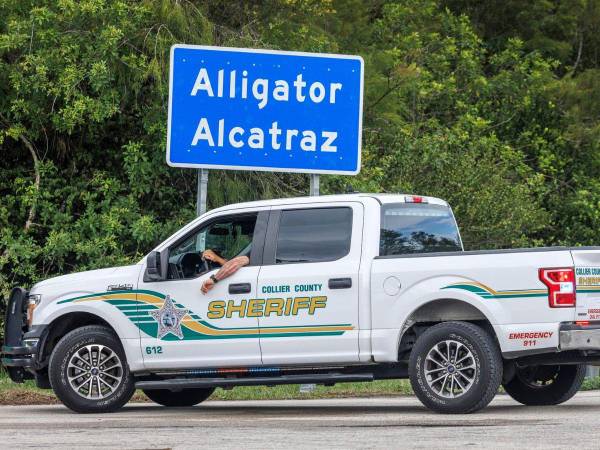 Agentes de policía frente a la señal de entrada de la polémica cárcel migratoria, Alligator Alcatraz.