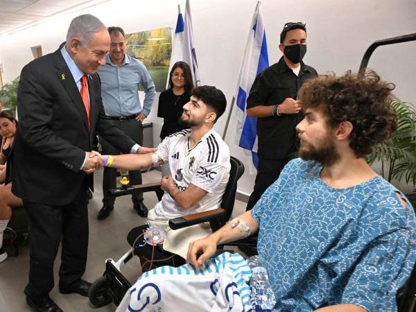 El primer ministro israelí, Benjamín Netanyahu (i), saluda a dos soldados heridos en el centro médico que acogerá y tratará a los rehenes israelíes que serán liberados por Hamás.