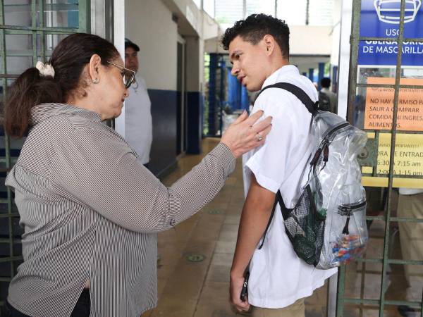 Una maestra revisa el uniforme y corte de cabello de un estudiante en San Salvador tras la implementación de un estricto control de disciplina que incluye un saludo respetuoso.