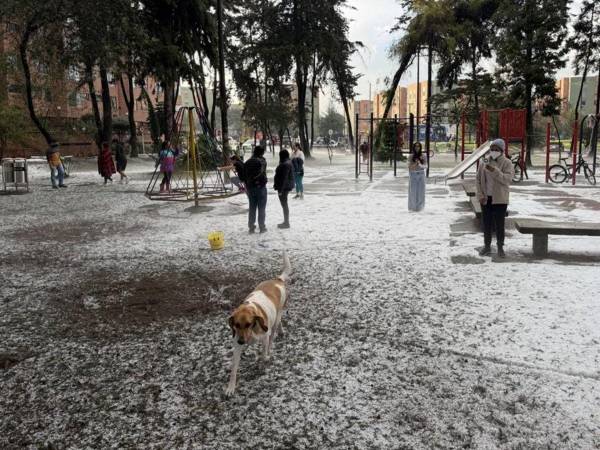 Personas juegan en un parque cubierto de granizo este lunes, en Bogotá (Colombia).
