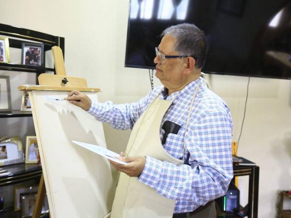 Héctor Manuel Borjas se prepara para iniciar una nueva pintura en la sala de su casa.