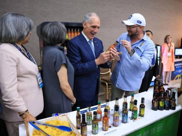 El presidente Nasry Asfura dialoga con un emprendedor en el Foro de Turismo. Observan la Canciller, Mireya Aguero y la presidenta del Cohep, Anabel Gallardo.