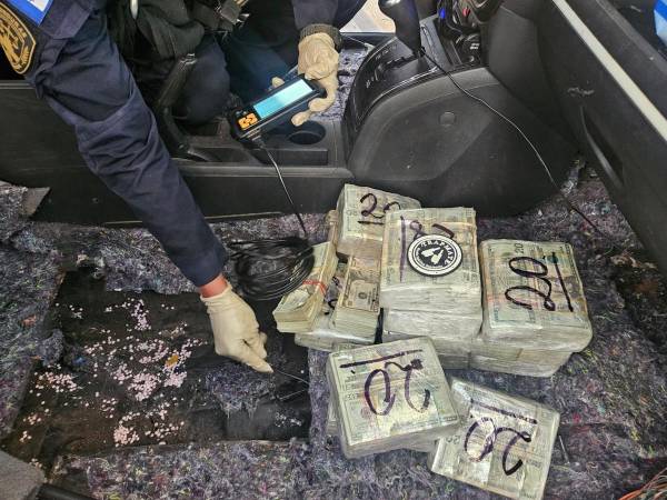 Agentes inspeccionan el vehículo decomisado en Guasaule, Choluteca, en busca de dinero oculto en un compartimiento detectado durante el operativo.