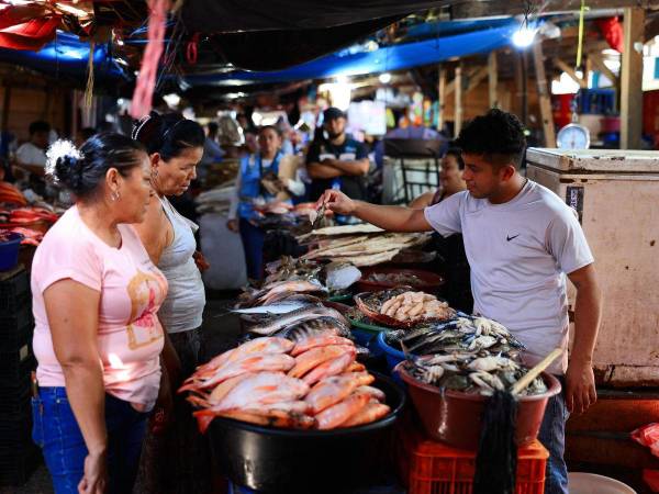 Vendedores y compradores negocian el precio del pescado en un mercado de San Pedro Sula.