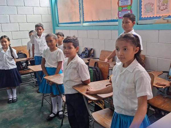 Estudiantes de un centro educativo público de pie mientras inician la clase.