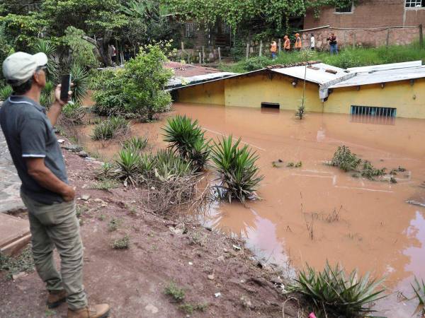Un hombre toma una fotografía de casas afectadas por las lluvias este domingo, en la aldea de Zarabanda, en el municipio de Santa Lucia.