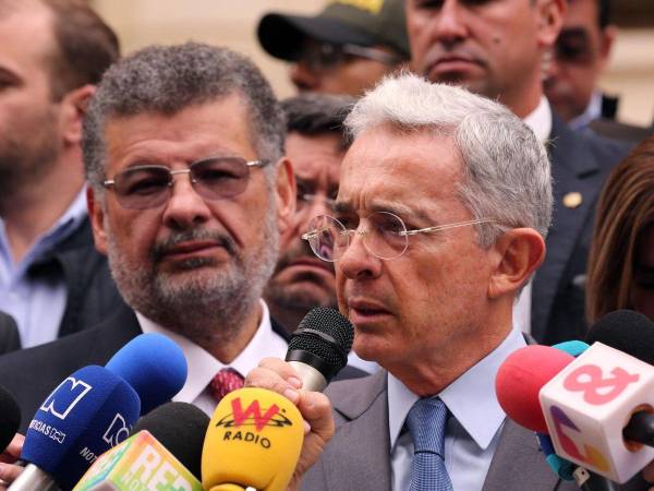 El expresidente Álvaro Uribe (d), habla con los medios de comunicación acompañado por el abogado Jaime Granados.