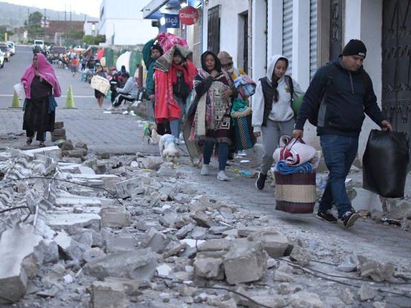Personas caminan con sus pertenencias por una calle tras los fuertes temblores este miércoles, en Palín, Guatemala.