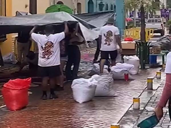 Feligreses de Comayagua luchan contra la lluvia para proteger las alfombras de aserrín.
