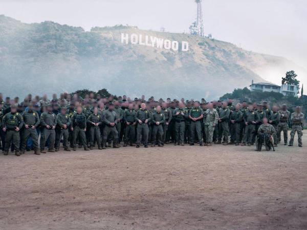 Decenas de agentes de la Patrulla Fronteriza de EEUU posan frente al icónico letrero de Hollywood de fondo.