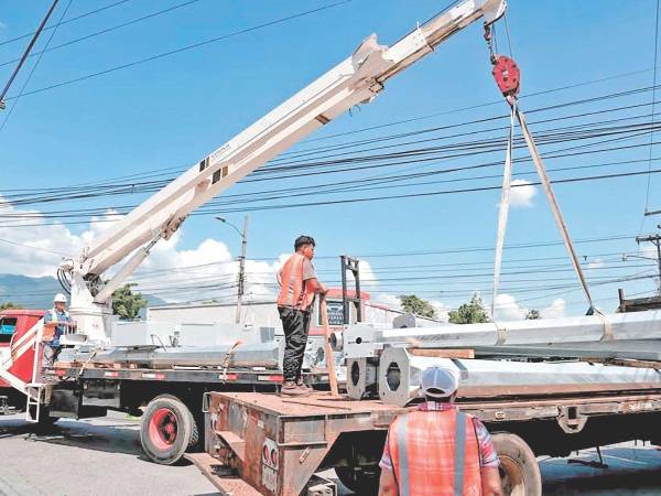 Trabajadores descargan postes de metal para la instalación de semáforos en San Pedro Sula
