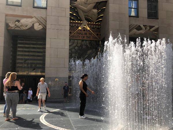 Unas personas se refrescan de la ola de calor dentro de las fuentes de agua pública en la plaza del Rockefeller Center en Nueva York.