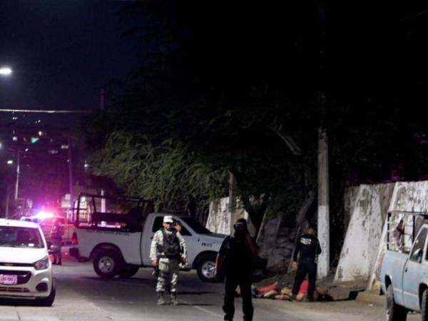 Agentes policiales mexicanos cubren la escena donde fueron encontrados los cuerpos.