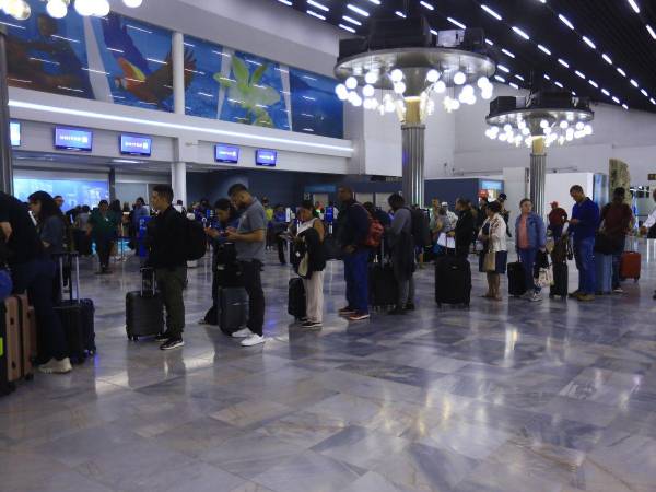 Pasajeros se forman en fila en el aeropuerto Ramón Villeda Morales una fotografía de archivo.