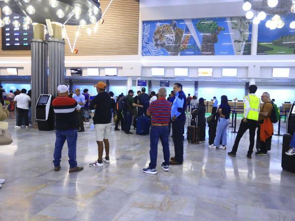 Personas esperan en el lobby del aeropuerto Ramón Villeda Morales.